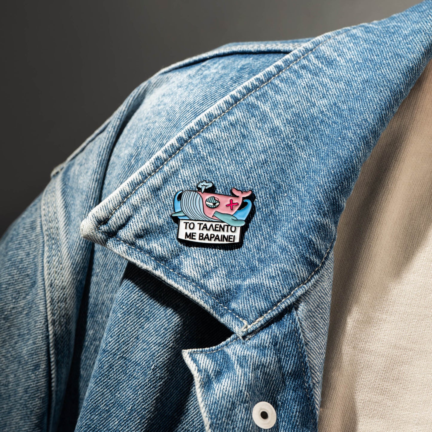 Denim jacket with a colorful enamel pin whale on a dark background