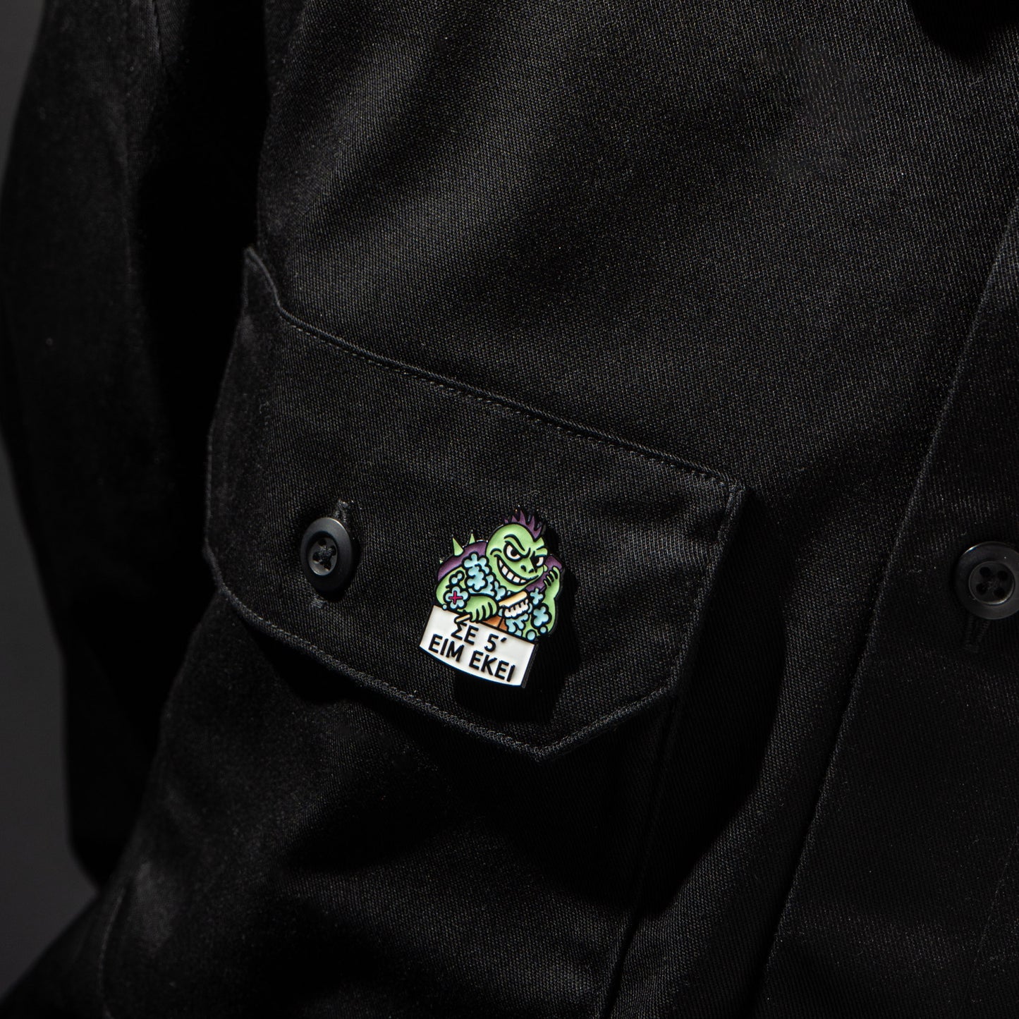 Enamel pin of a turtle on a black jacket with a dark background