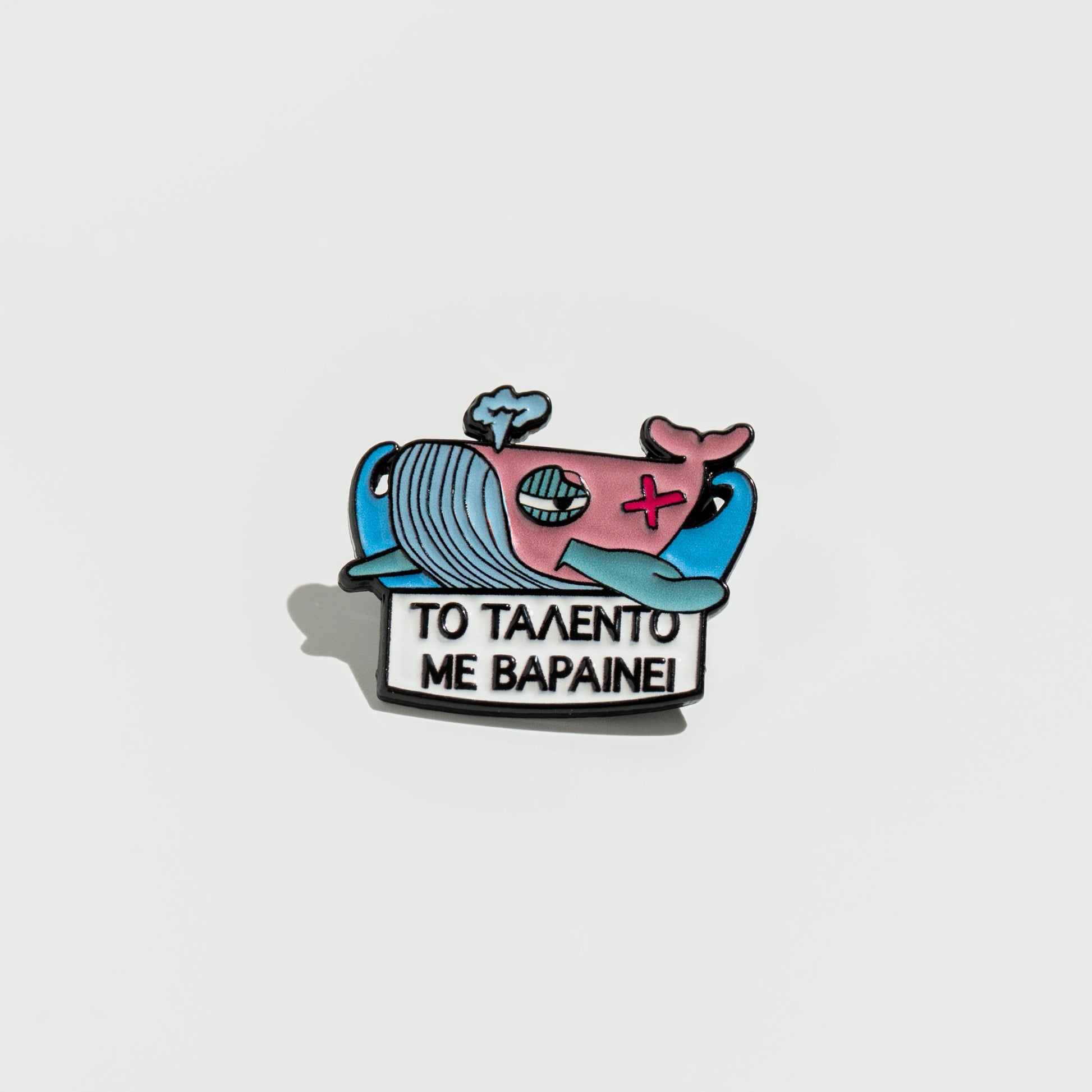 Enamel pin with cartoon whale design on a white background