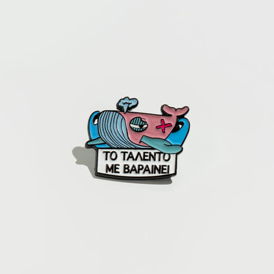 Enamel pin with cartoon whale design on a white background